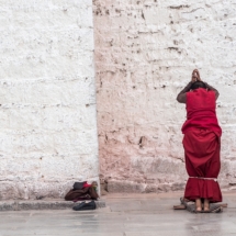Un moine prie et se prosterne devant le temple du Jokhang. /